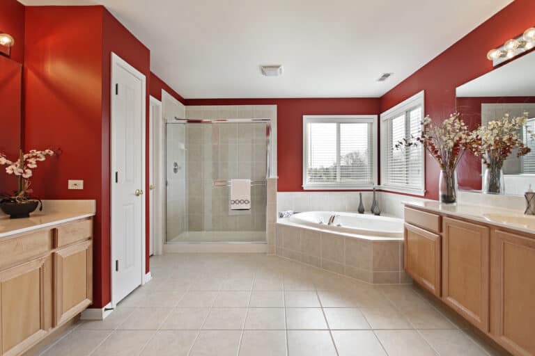 Spacious bathroom with red walls and nicely installed vanity tops and cozy bathtub